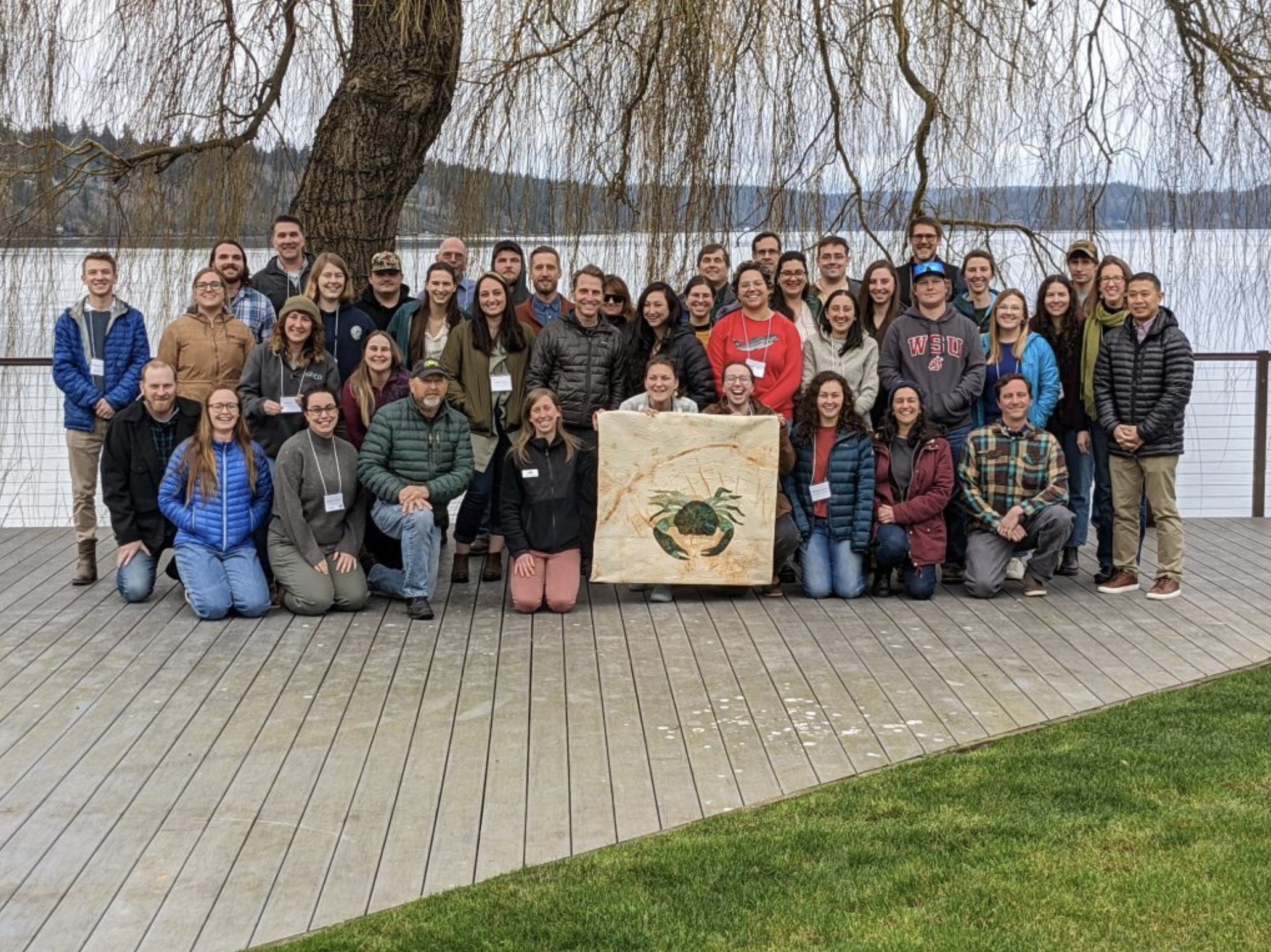 2023 Trappers' Summit attendees gathered around a green crab banner.<br />
