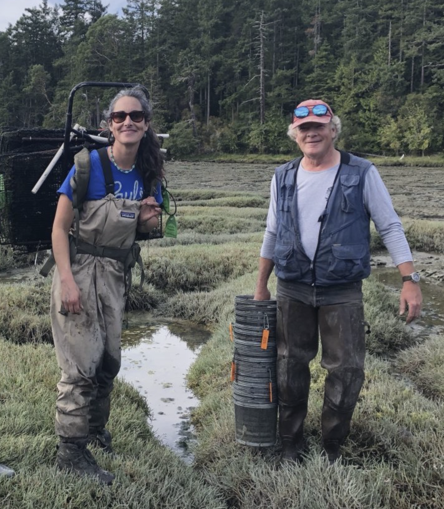 Erin Holcomb (L) and Mark Donohue (R) heroically carrying huge stacks of traps through the mud. 